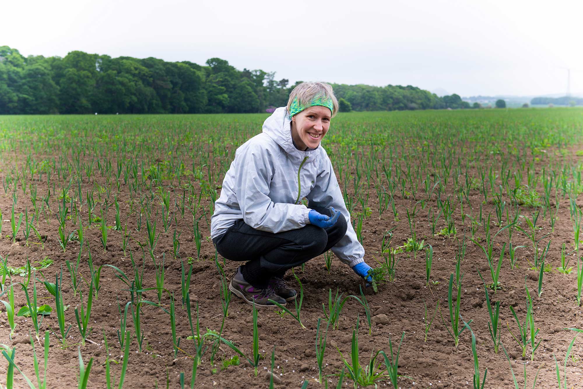 Woman smiling in field while picking crops.